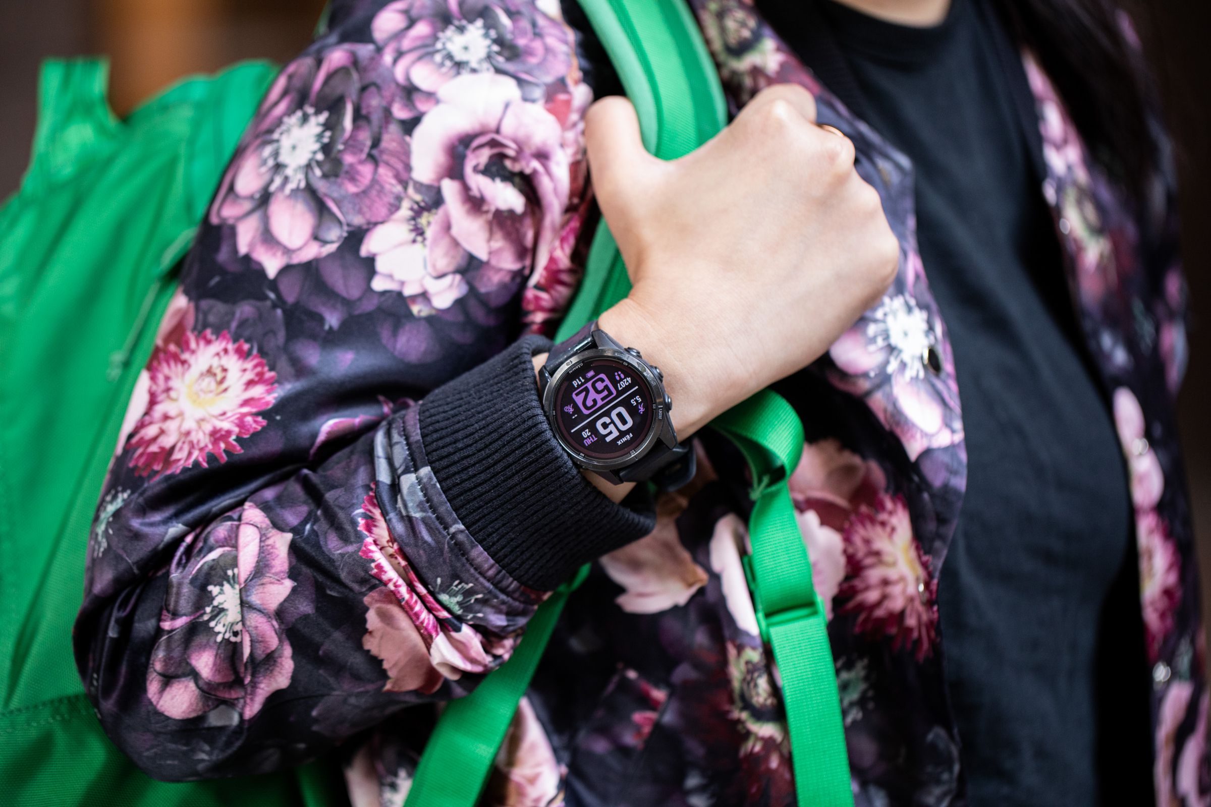 Person wearing a floral jacket and bright green backpack with a Garmin Fenix 7S Pro on their wrist