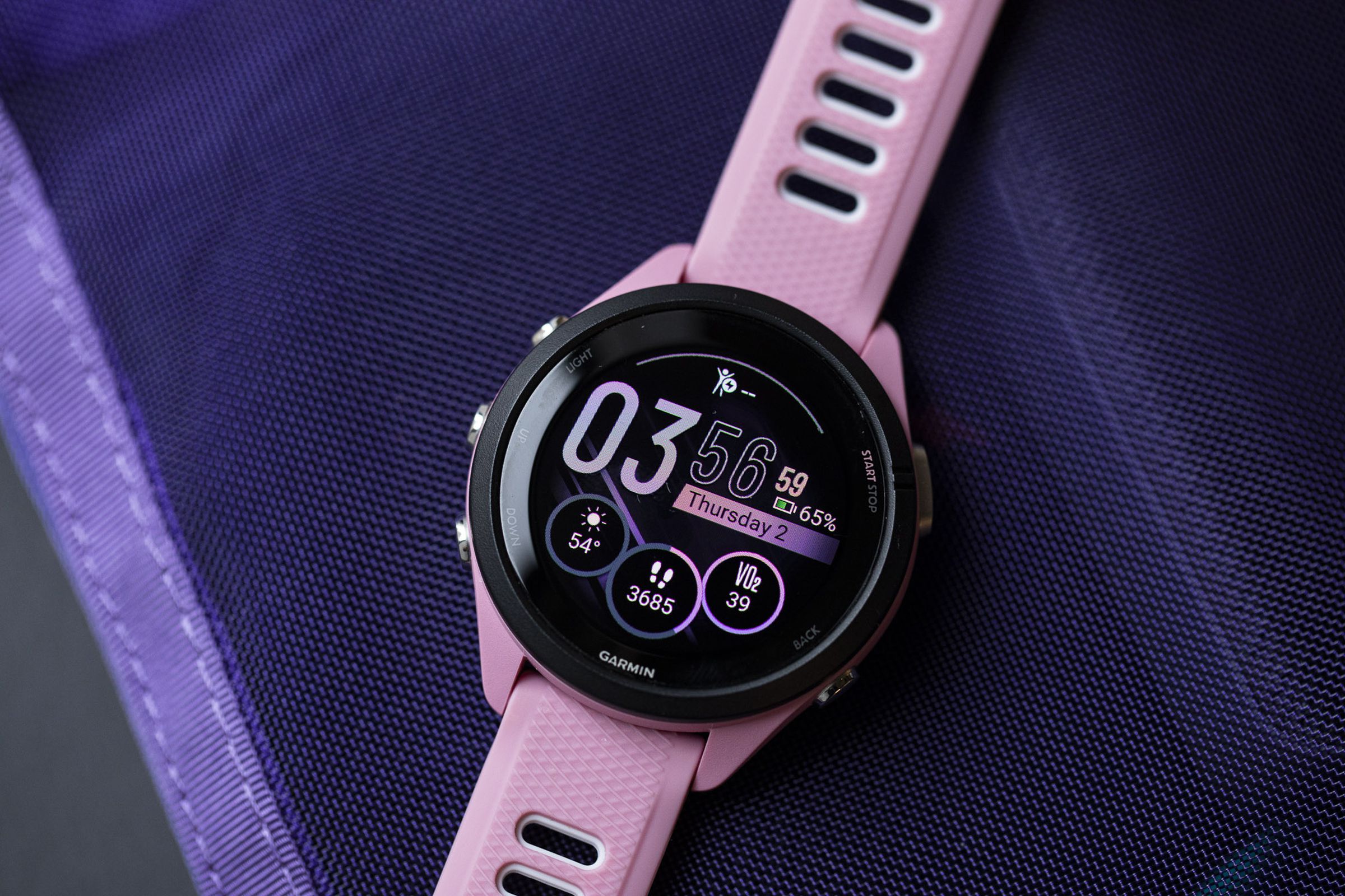 Close-up of the Garmin Forerunner 265S’s OLED display and watchface on a purple background